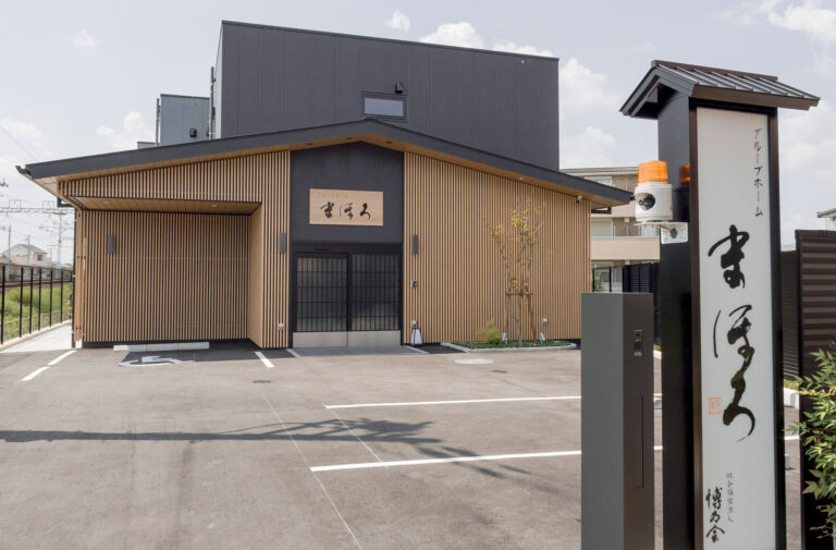 木製格子と瓦屋根を配した和風デザインの施設入口。駐車場が見える。